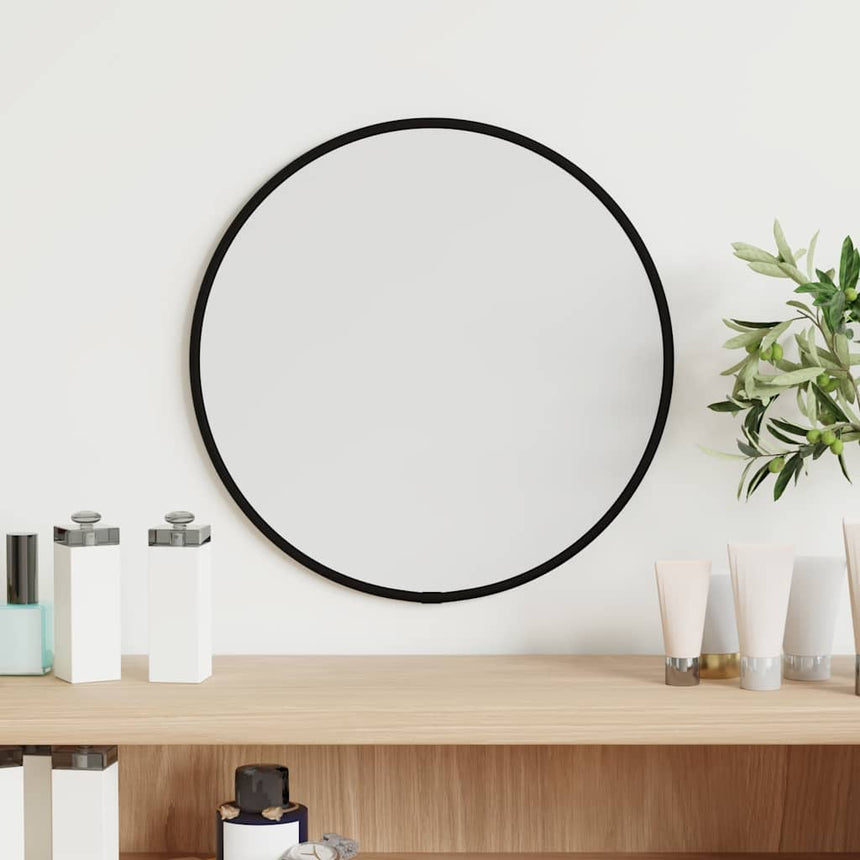A small round wall mirror in a slim black frame