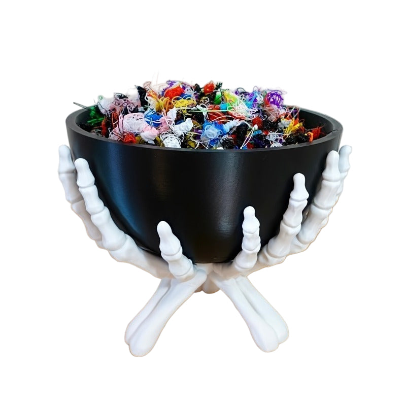 Black bowl of candy held by white skeleton hands