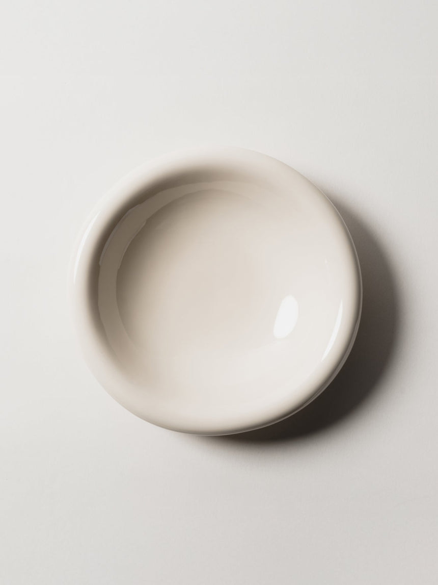 A handmade ceramic bowl in white, wide and shallow, seen from above