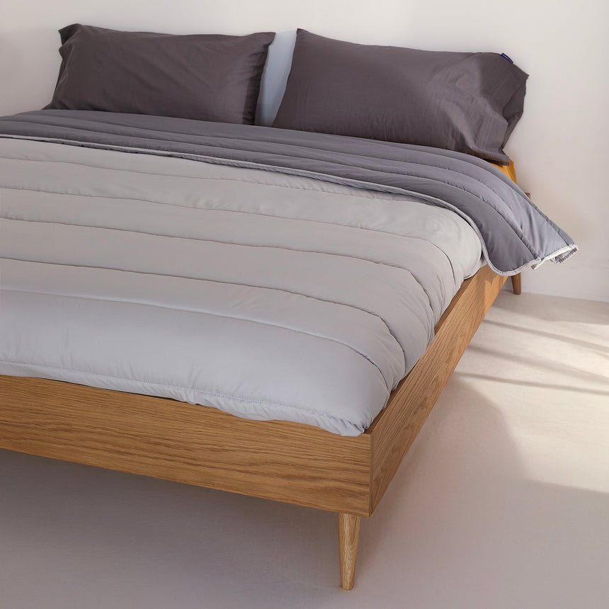 Reversible quilted comforter in light and dark grey on a bed