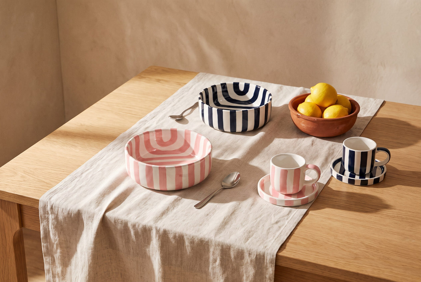 Pink and navy striped ceramic bowls and espresso cups with a bowl of lemons
