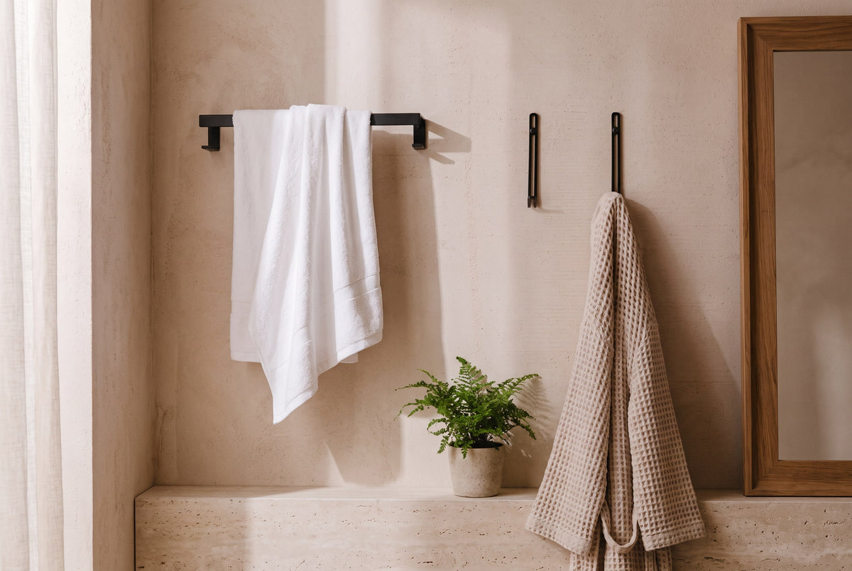 Black square-profile towel rail and wall hook holding a towel and waffle robe