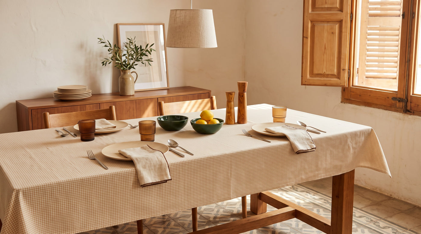 Dining table laid with ceramic plates, linen napkins and olive wood mills in a Catalan flat with wooden shutters and cement floor tiles