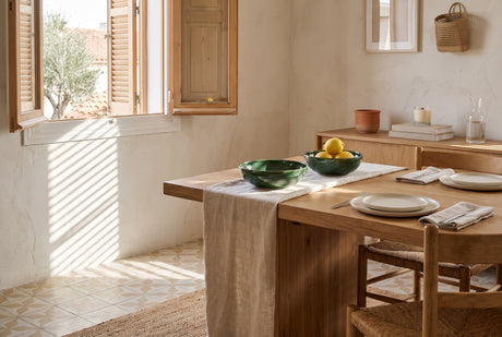 Medina green ceramic bowls on a wooden dining table in a Catalan flat with louvred shutters