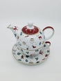 White porcelain teapot stacked on a cup, printed with red and green Christmas motifs