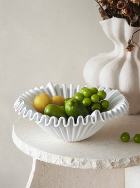 White pleated resin fruit bowl filled with lemons and grapes
