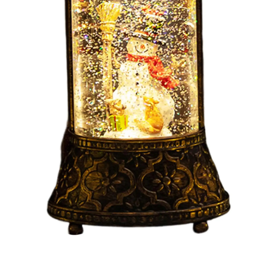 Lit snow globe lantern with a snowman inside on a bronze-coloured base