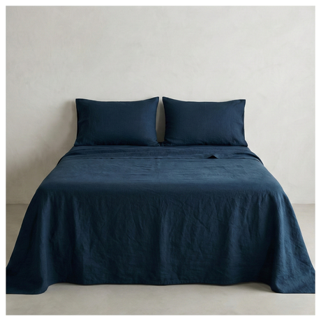 A navy blue linen-cotton sheet set made up on a bed, shown from the front