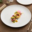 Round white porcelain plate with an embossed dotted surface and gold dots