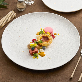 Round white porcelain plate with an embossed dotted surface and gold dots