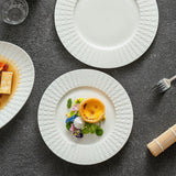 White ceramic plate with an embossed woven rim holding a custard tart