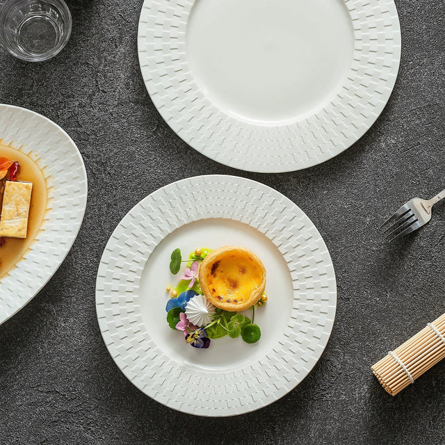 White ceramic plate with an embossed woven rim holding a custard tart