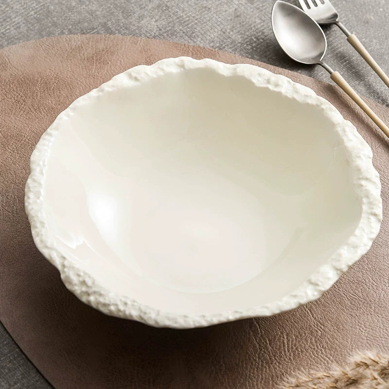 Ivory porcelain bowl with a rough stone-textured rim holding a prawn salad
