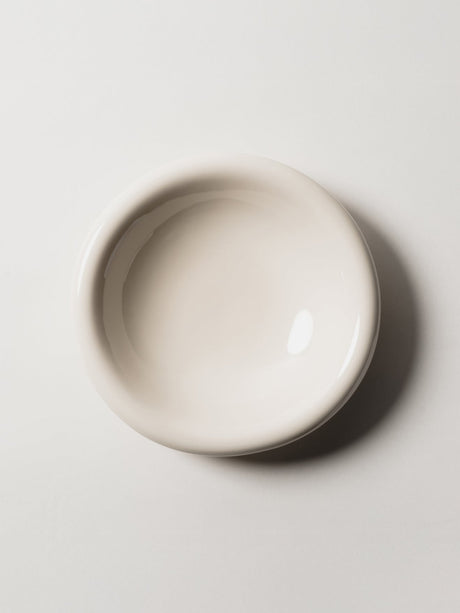 A handmade ceramic bowl in white, wide and shallow, seen from above