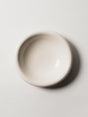 A handmade ceramic bowl in white, wide and shallow, seen from above