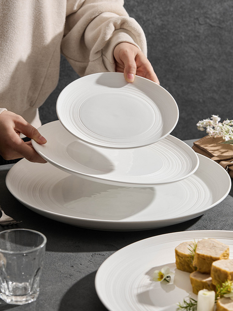White ceramic dinner plate with fine concentric lines and a plated terrine