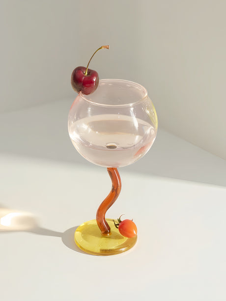 Hand-blown wine glass with a clear round bowl, an orange wavy stem and a yellow foot
