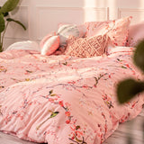 A cotton duvet cover printed with cherry blossom branches, made up on a bed