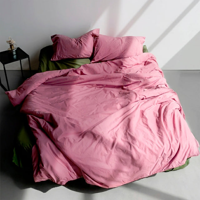 A duvet cover in a bright pink-purple, made up on a bed