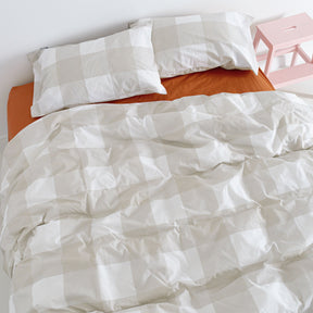 A cotton duvet cover in a beige and white vichy check, made up on a bed