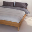 Reversible quilted comforter in light and dark grey on a bed