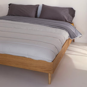 Reversible quilted comforter in light and dark grey on a bed