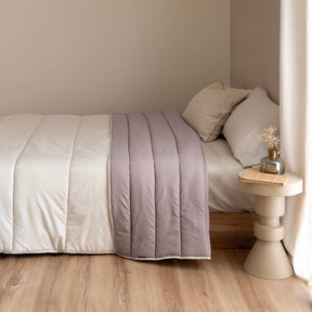 Reversible quilted comforter in beige and taupe on a bed