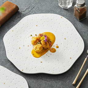 White porcelain plate with a wavy edge, a dotted rim and gold specks