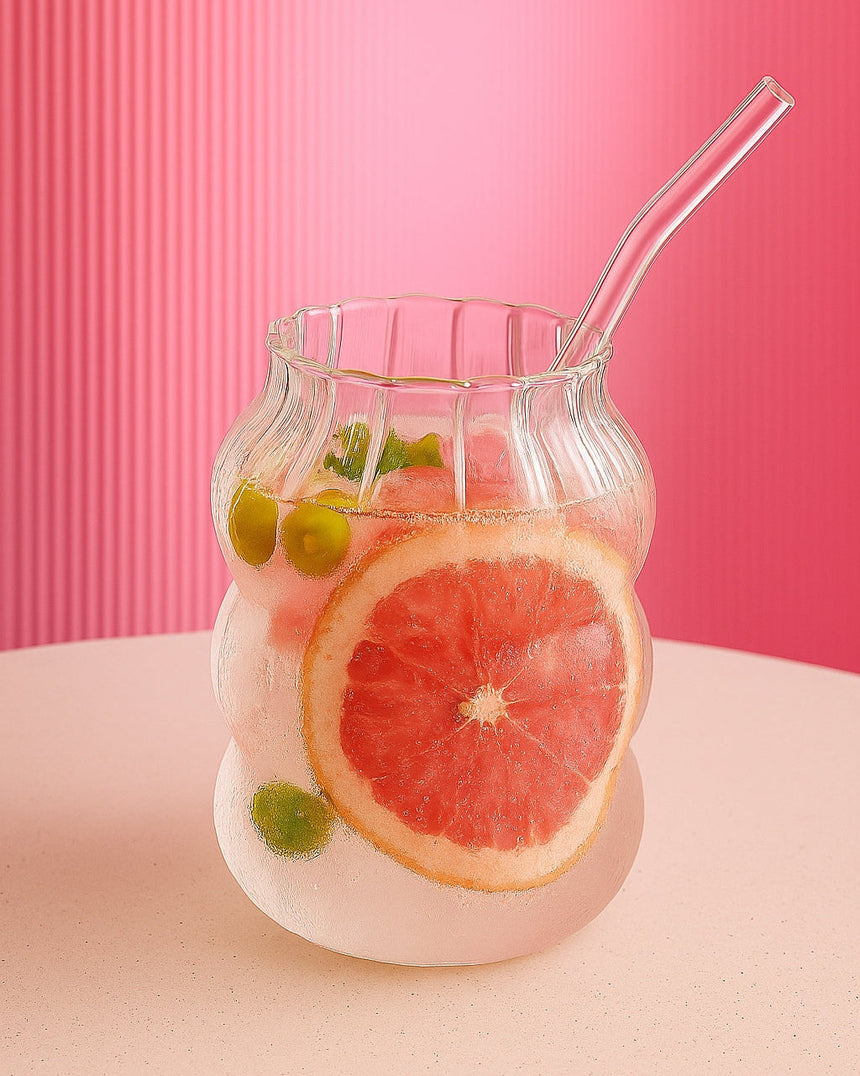 Ribbed bubble-shaped glass cup with a glass straw and grapefruit slices