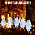 Five white ghost solar lights on stakes in a garden at night