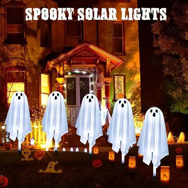 Five white ghost solar lights on stakes in a garden at night