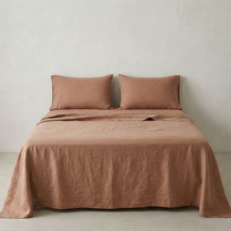 A terracotta brown linen-cotton sheet set made up on a bed, shown from the front