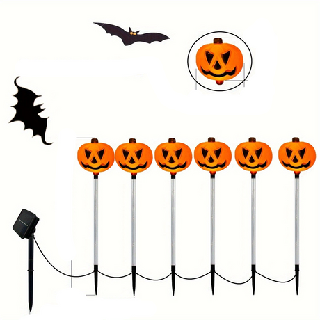 Six pumpkin face garden lights on stakes with a solar panel
