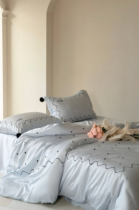 Pale stone blue lyocell duvet cover set with black polka dots, wavy line embroidery and pompoms