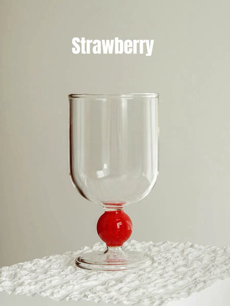 A clear wine glass with a red gumball stem