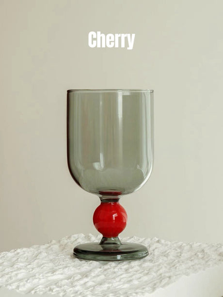A smoke grey wine glass with a red gumball stem