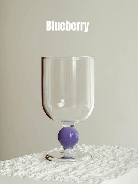 A clear wine glass with a purple gumball stem