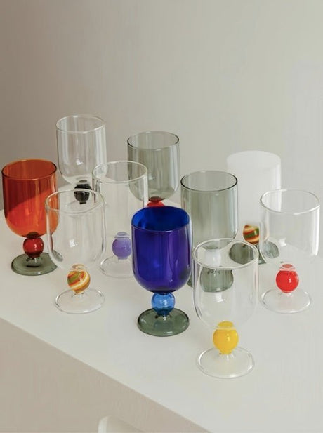 A group of the wine glasses in different bowl colours arranged together on a shelf