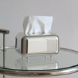 Mirror silver tissue box cover with tissues on a glass side table