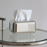 Mirror silver tissue box cover with tissues on a glass side table