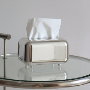 Mirror silver tissue box cover with tissues on a glass side table