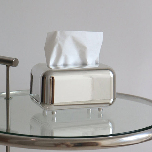 Mirror silver tissue box cover with tissues on a glass side table