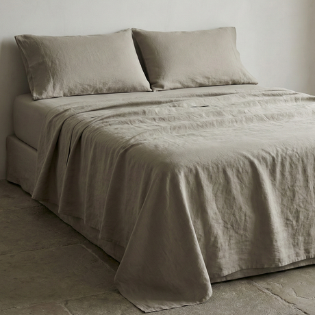 A taupe linen-cotton sheet set made up on a bed, seen at an angle