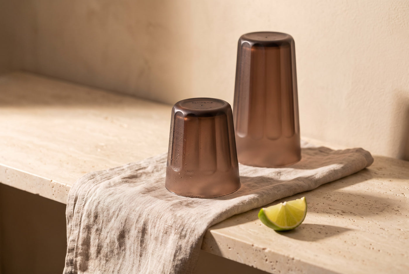 Chocolate-brown plastic tumblers air-drying upside down on a damp linen cloth